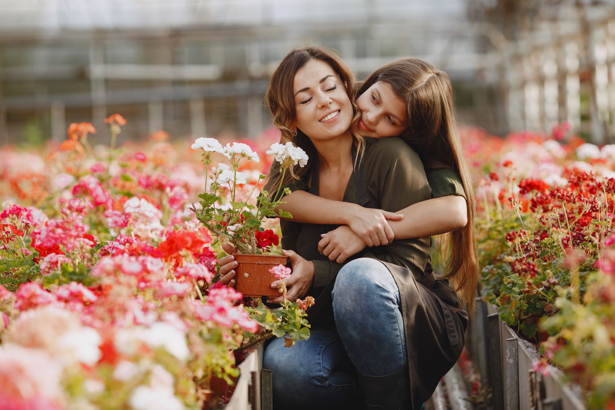 Mutter und Tochter umarmen sich lachend zwischen Blumen